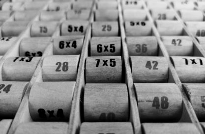 Black and white photo of wooden blocks with times tables on used in the GesherEU blog Learning Times Tables at 23
